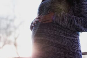 A pregnant woman with her hands on her baby bump.